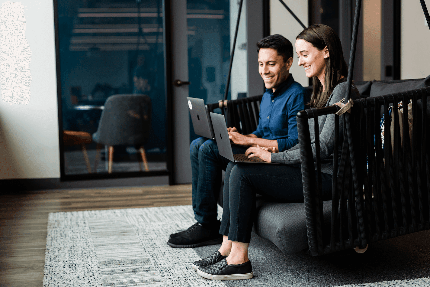 two people working on laptops from an office couch